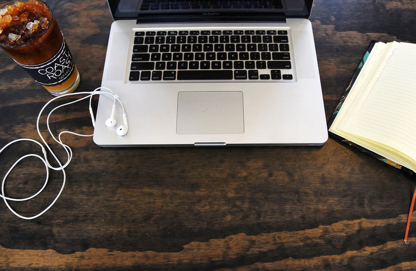Laptop and Coast Roast iced coffee on a dark wood table at St. Roch Market