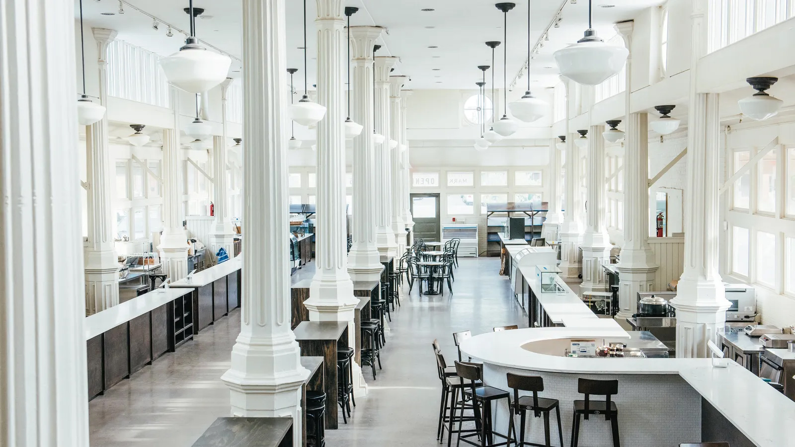 Inside St. Roch Market: white cast iron columns, pendant lights, and vendor counters